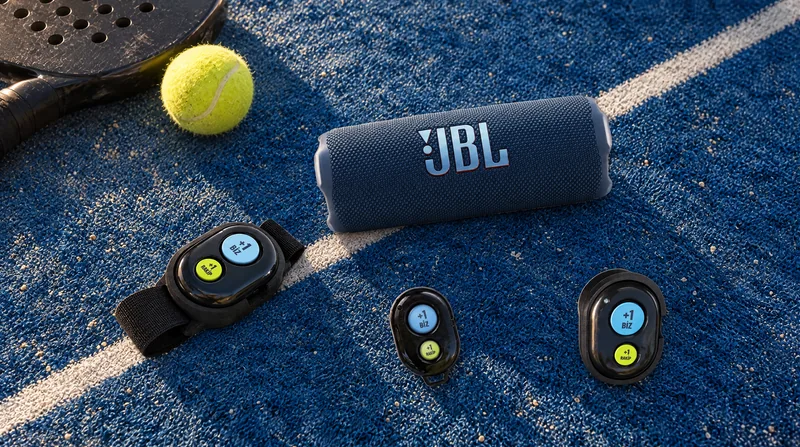 Kort zemininde JBL Flip 7 hoparlör ile kayışlı, mıknatıslı ve sade Bluetooth kumandalar