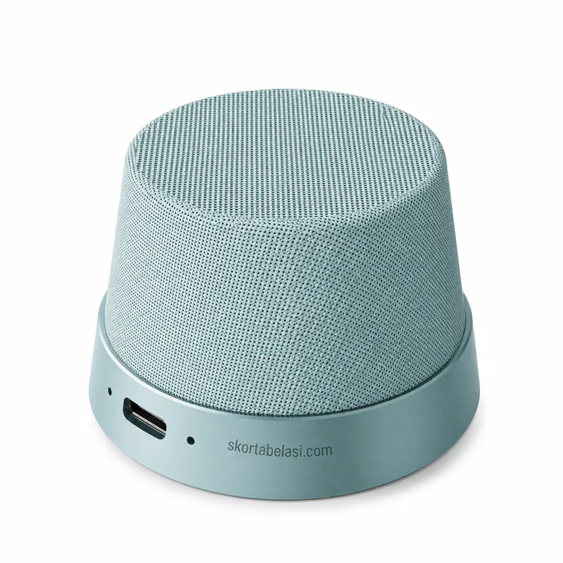Altavoz Bluetooth portátil redondo forrado en tela verde menta, con puerto USB-C en la base